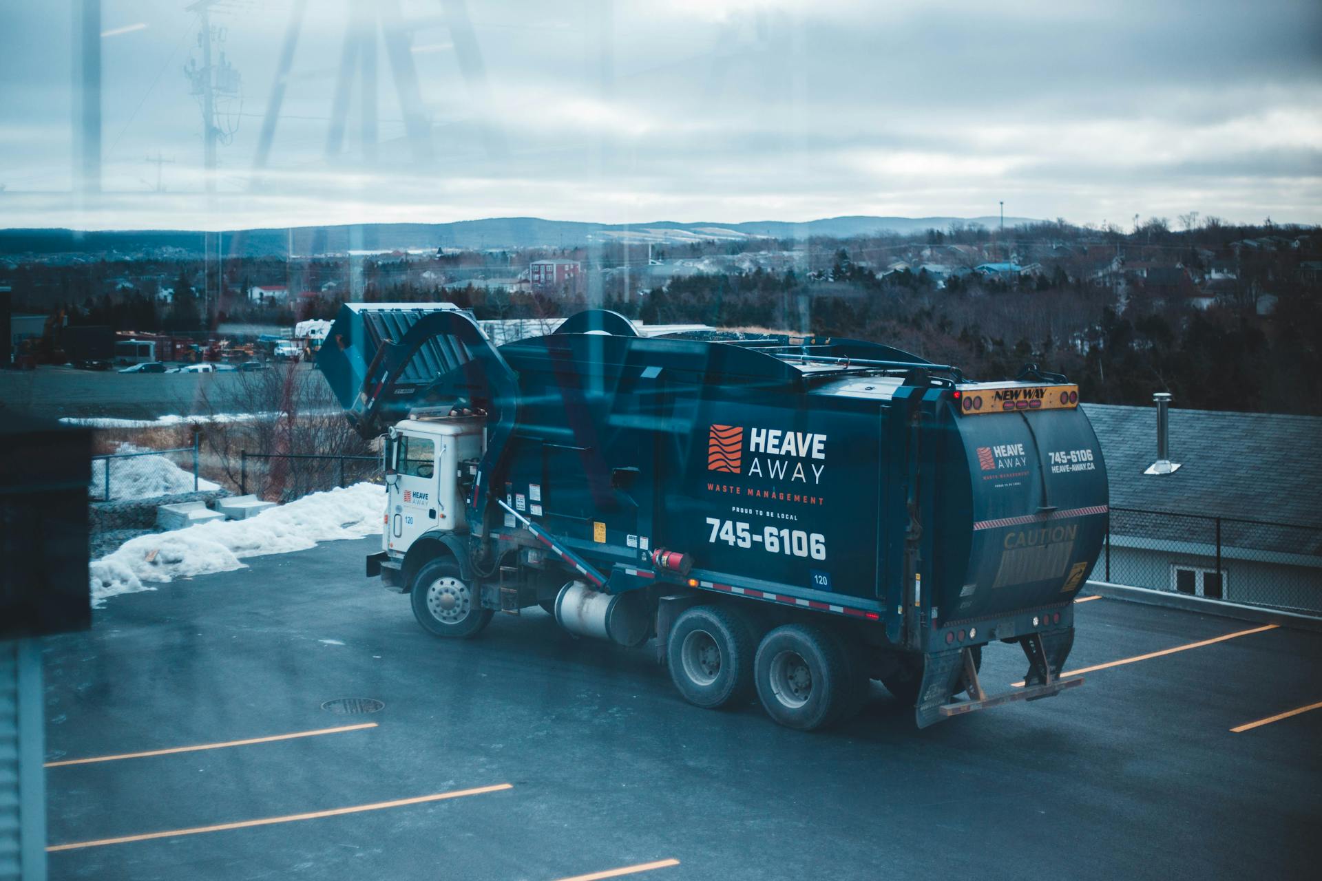 A waste management truck parked in a snowy lot, showcasing logistics in winter.