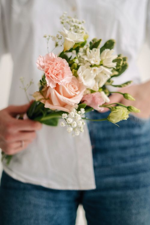 Free Delicate flower bouquet with pastel roses and baby's breath held by person in casual attire. Stock Photo