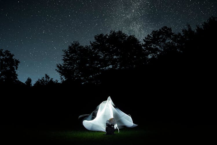 White Image Behind A Woman Squatting On Grass