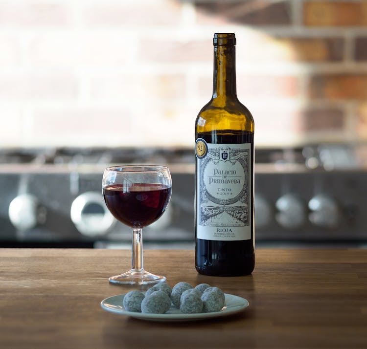 A Bottle And A Glass Of Red Wine On A Wooden Table