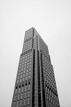 Low angle view of a modern skyscraper with copy space against a white sky.