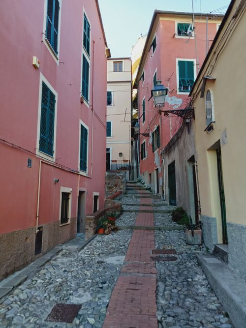 Free Cobblestone alley in Genoa with pastel buildings reflecting Ligurian charm. Stock Photo