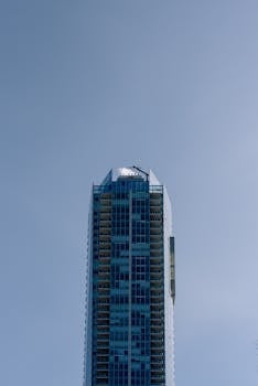Tall modern skyscraper with glass facade set against a clear blue sky.