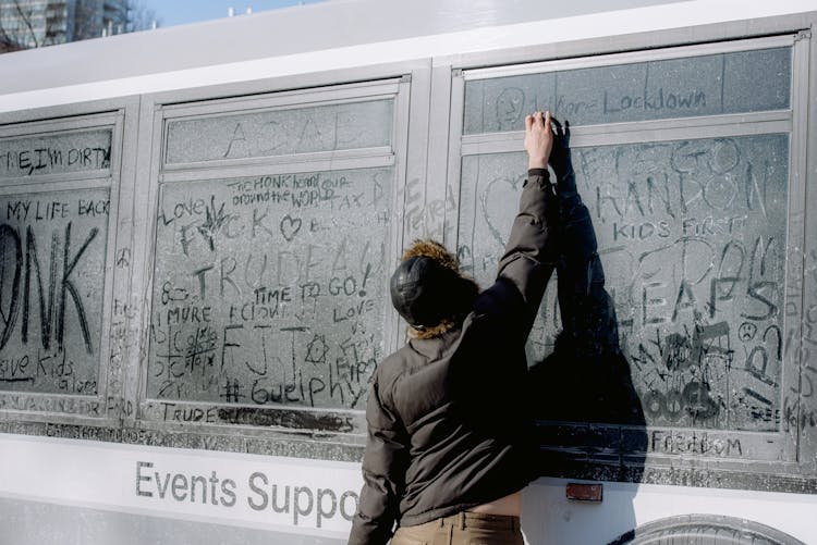 Man Writing On A Dirty Bus Window 