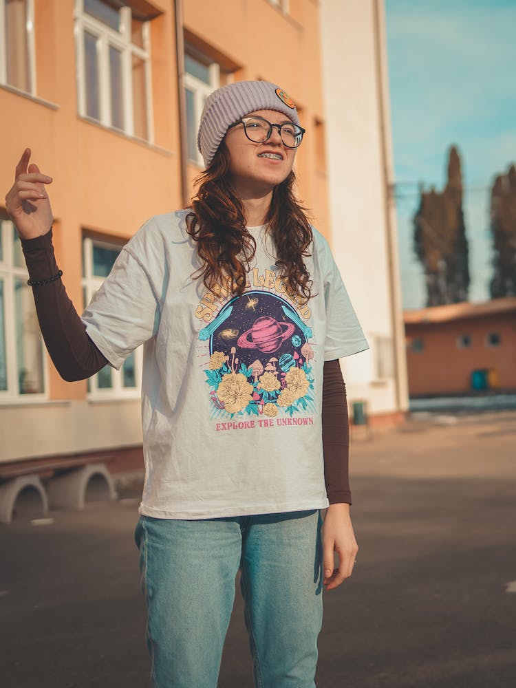 Girl Wearing T-Shirt With Graphics Standing In Front Of A School