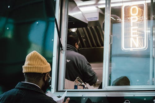 Free A Man in a Beanie Standing in front of a Food Truck Stock Photo