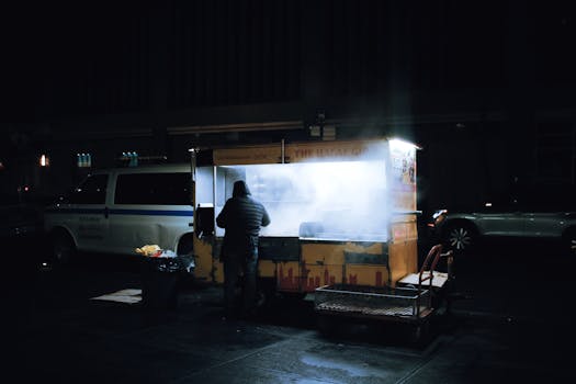 A street vendor prepares food at a night market with illuminated smoke.