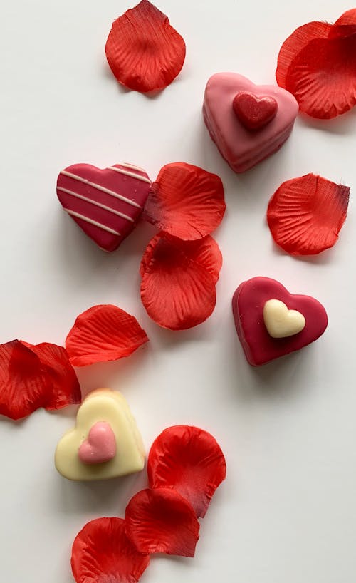 Heart-Shaped Chocolates and Red Petals on White Background