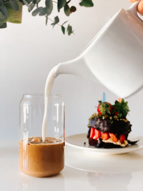 Pouring Milk into Glass Jar with Coffee