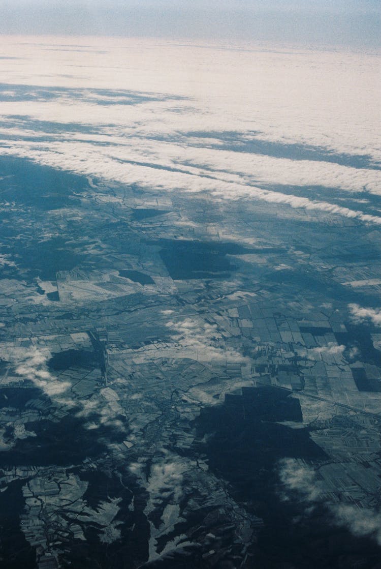 Aerial Shot Of Land And Water In Clouds