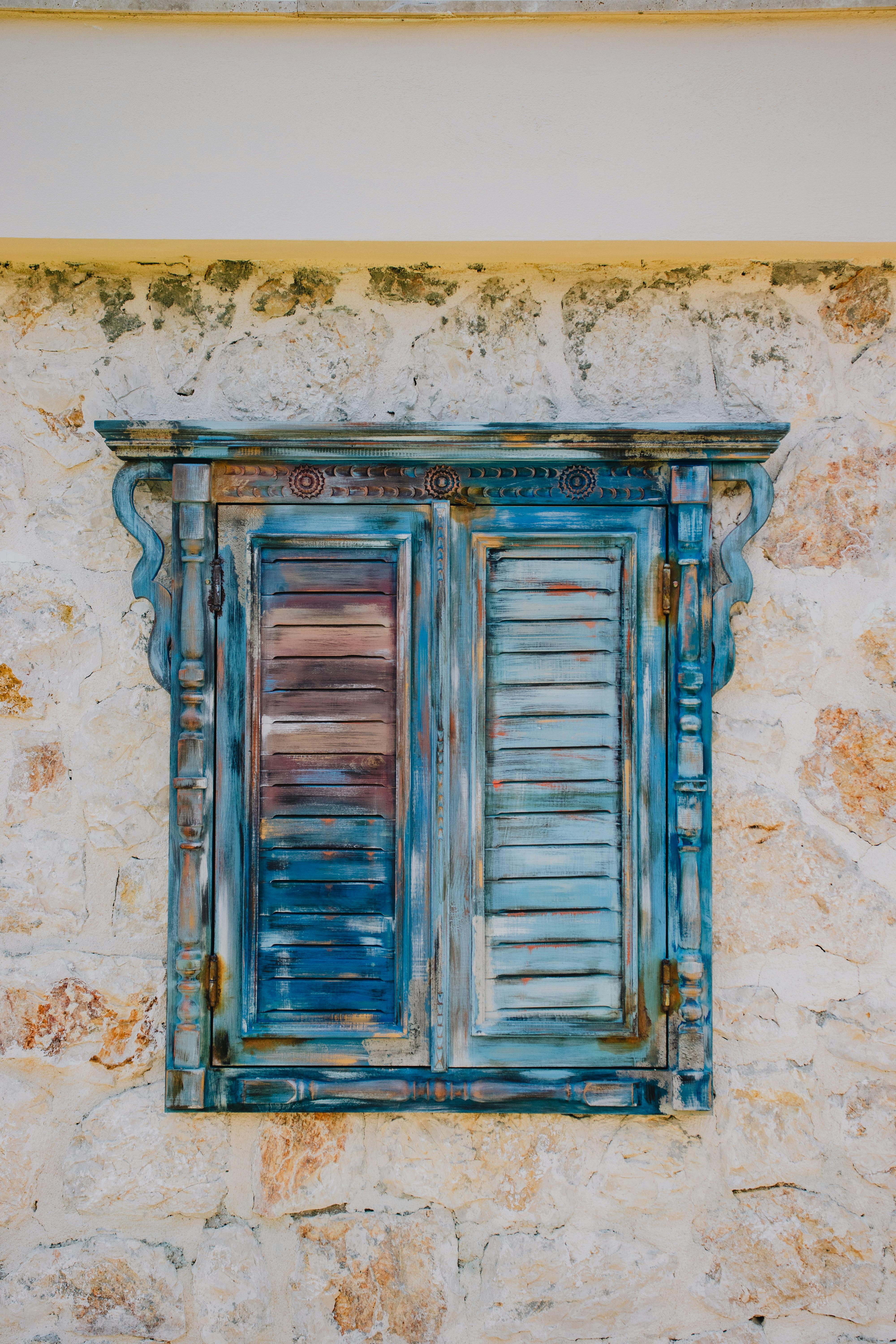 Vintage blue painted shutters on a rustic stone wall evoke timeless charm.