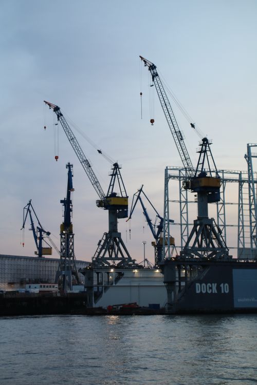 Free Industrial cranes at Hamburg harbor captured during dusk, highlighting logistics and transportation. Stock Photo