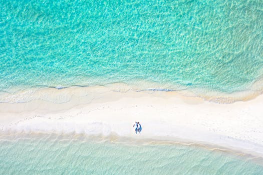 Aerial shot of a couple lying on a pristine beach with turquoise sea.