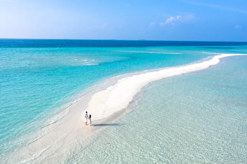 Couple on Sandy Beach Surrounded by Beautiful Blue Ocean