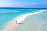 Couple on Sandy Beach Surrounded by Beautiful Blue Ocean