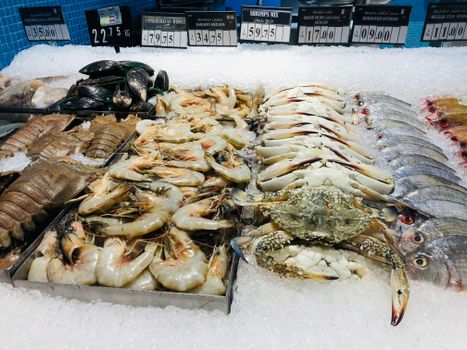 Close-up of fresh seafood including shrimps, crabs, and fish on ice at a market.
