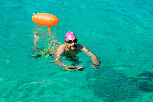 Free A man swimming in the clear turquoise waters of Cozumel, wearing goggles and a pink swim cap. Stock Photo