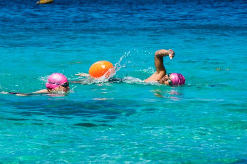 Free Two athletes swimming in clear blue waters with pink caps in Cozumel, Mexico. Stock Photo