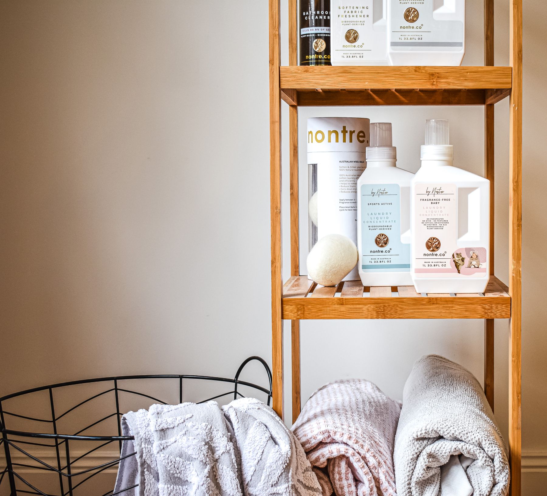 Warm bathroom with bamboo shelves holding towels, toiletries and simple bath essentials