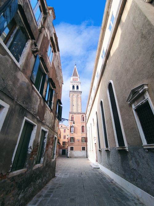 Free A captivating view of St Mark's Campanile from an alley in Venice, Italy. Stock Photo