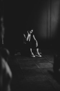 A thoughtful woman sitting indoors in a monochrome setting, expressing introspection and solitude.