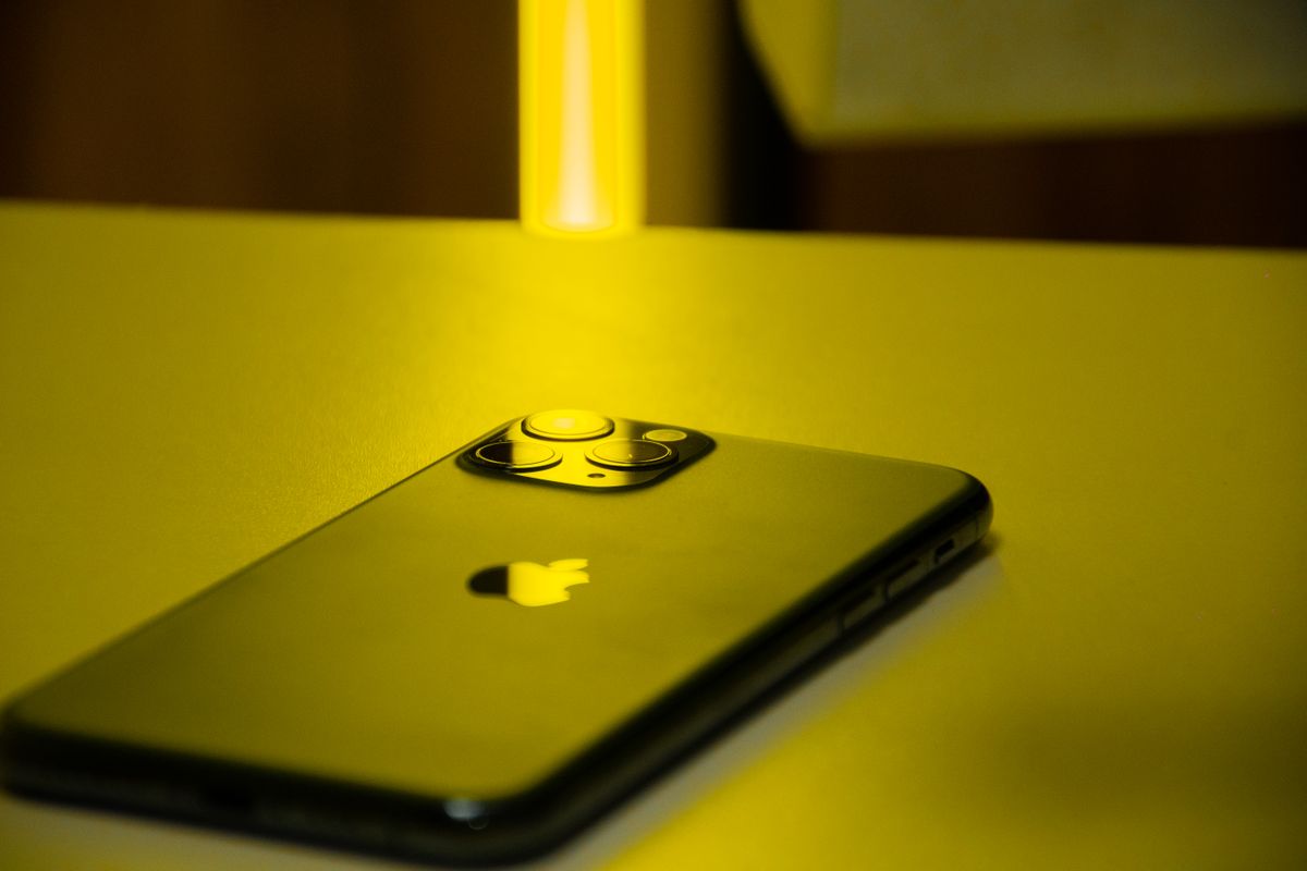 Stylish close-up of a smartphone under yellow lighting, highlighting design and technology.