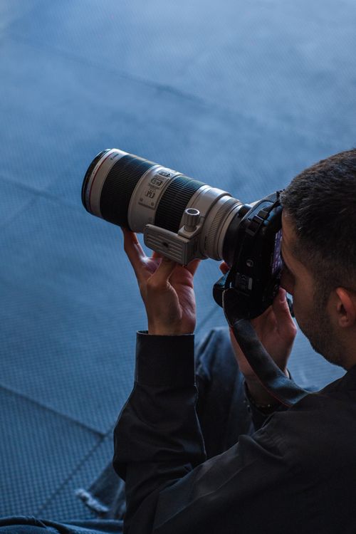 Free Photographer capturing images using a telephoto lens, angled view. Stock Photo