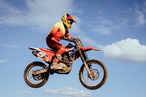 Free Man in Red and Black Motocross Suit Riding Motocross Dirt Bike Stock Photo