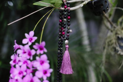 Free Close-up of violet orchids with decorative prayer beads in a peaceful garden. Stock Photo