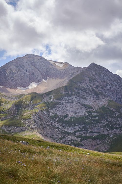 Free Captivating view of lush fields and rugged mountains under white clouds in Adygeya. Stock Photo