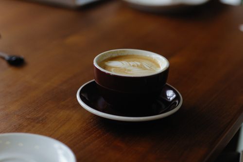 Free Latte with art in a ceramic cup on a wooden table, warmth in simplicity. Stock Photo