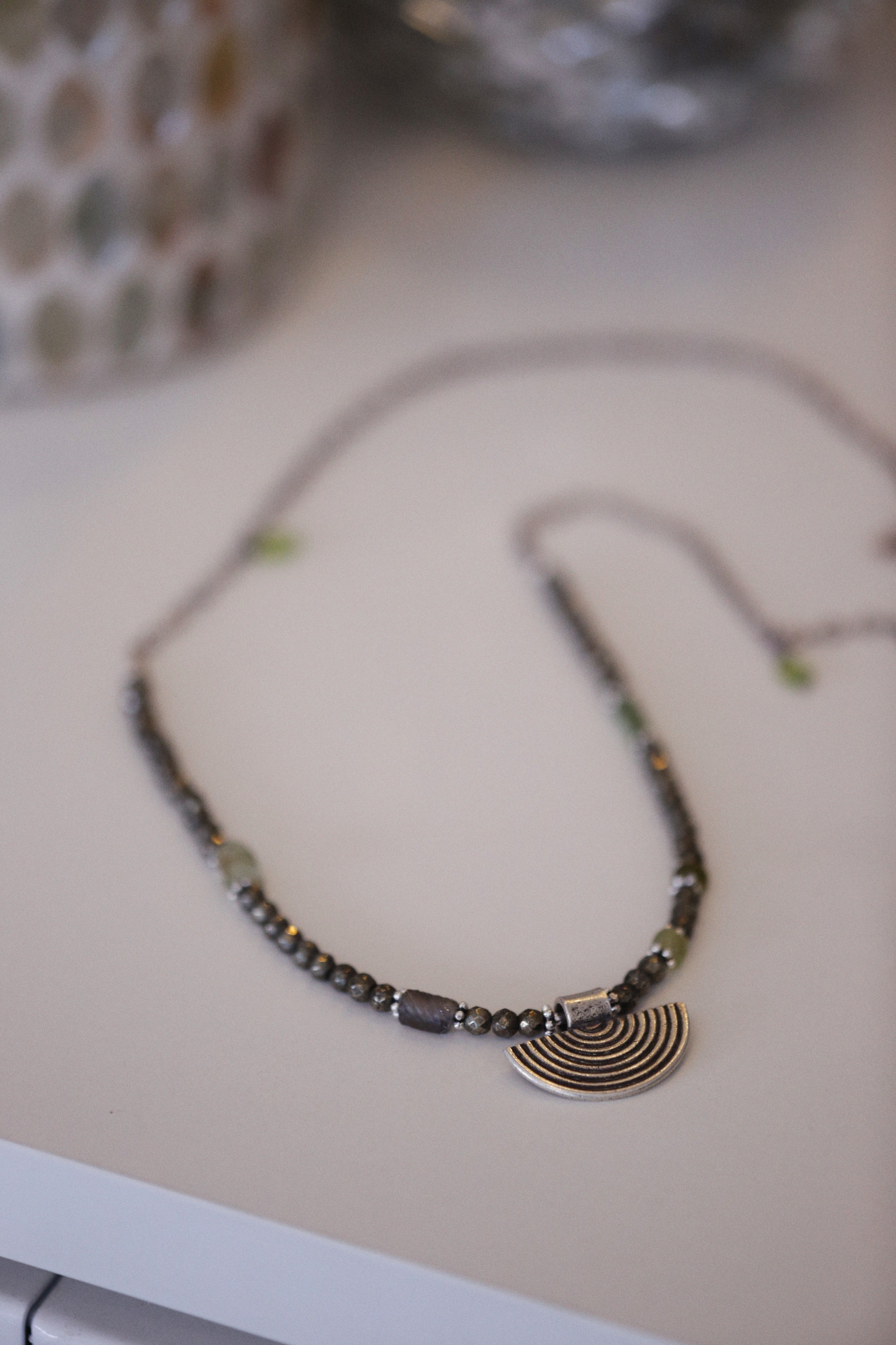 Elegant silver beaded necklace with a spiral pendant on a white background.
