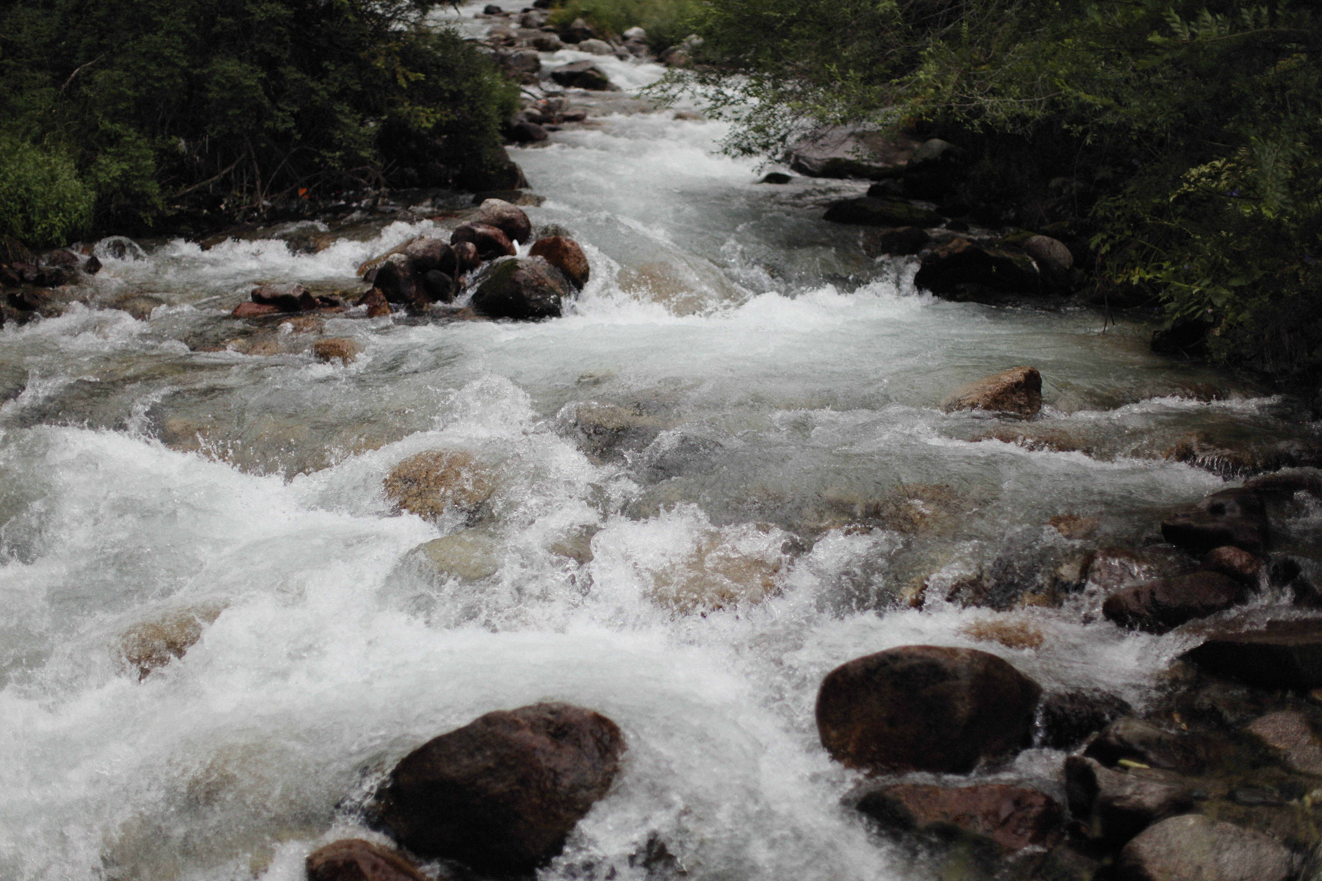 A River Flowing Through Rock Boulders · Free Stock Photo