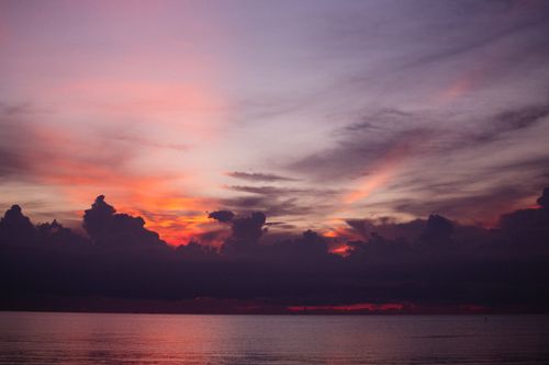 Free Stunning sunset view with dramatic clouds over a tranquil ocean, captured during golden hour. Stock Photo