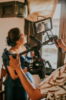 A woman in a blue dress is filmed with a gimbal-mounted camera, capturing a behind-the-scenes moment.