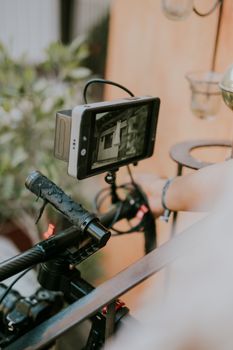 A detailed view of a camera rig with a mounted digital display screen outdoors.