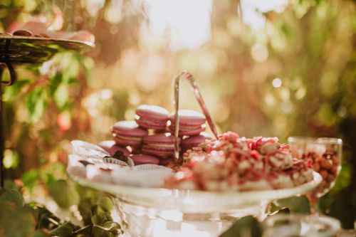 Free A beautifully arranged dessert table featuring glassware and colorful macarons set in a lush outdoor setting. Stock Photo