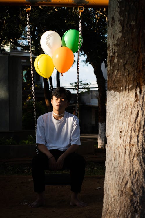 A Man in White Shirt Sitting on a Swing