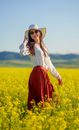 Smiling Woman in Sunglasses and White Hat Standing in Meadow