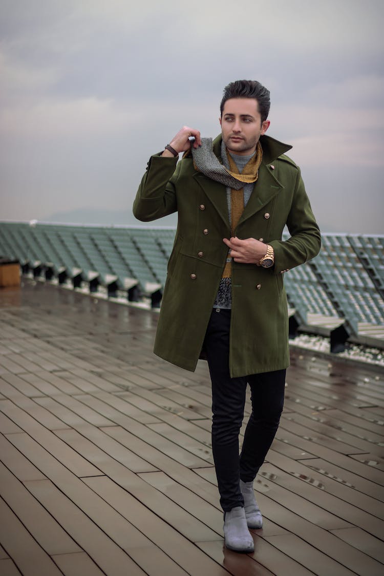 Man In Green Coat Walking While Looking Sideways 