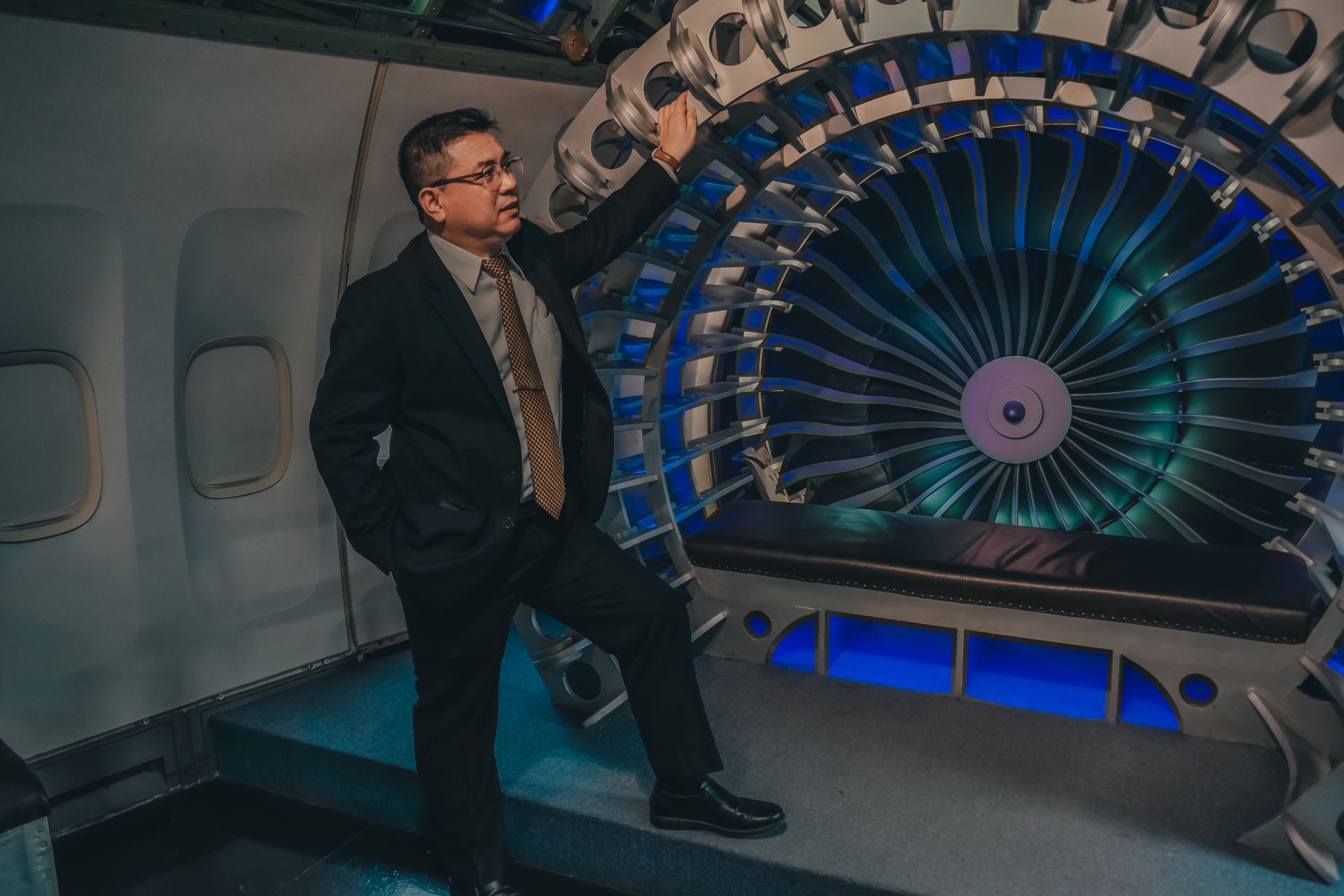 A business professional in a suit examining the intricate details of a turbine engine interior.