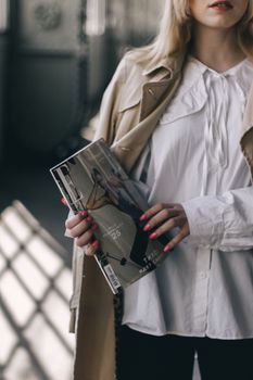 Elegant woman holding a fashion magazine with a chic outfit indoors, perfect for lifestyle imagery.