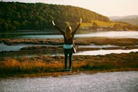 日落时分，一名女子张开双臂，静静地站在湖畔，拥抱大自然的美丽