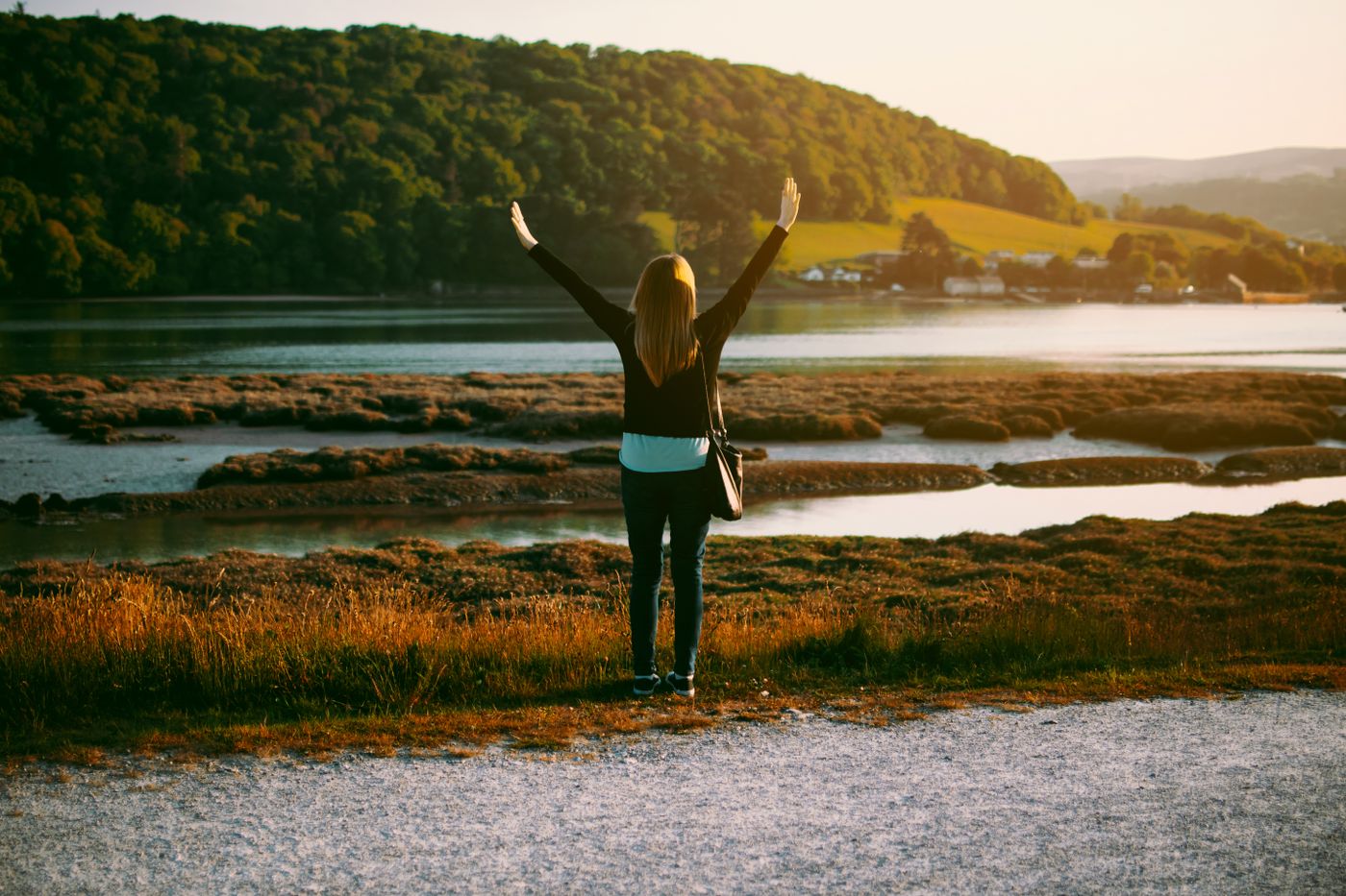 Woman with open arms beside a lake in autumn