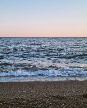 Peaceful scene of waves gently hitting the shoreline during sunset, perfect for relaxation themes.