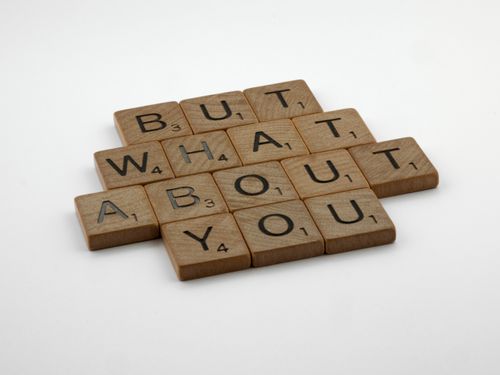 Free Close-up of wooden Scrabble tiles spelling 'But What About You' on a white surface. Stock Photo