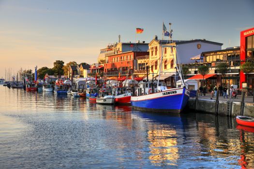 Colorful boats docked at Rostock harbor with sunset reflecting on the calm sea.