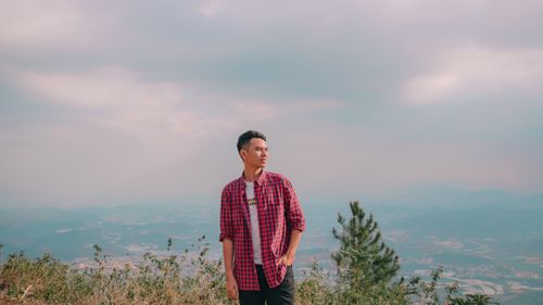 Free Portrait of a young man in a red plaid shirt on a scenic mountain landscape. Stock Photo
