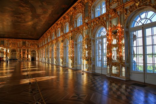 Lavish gilded interior of a historic St. Petersburg palace with intricate architecture and parquet flooring.