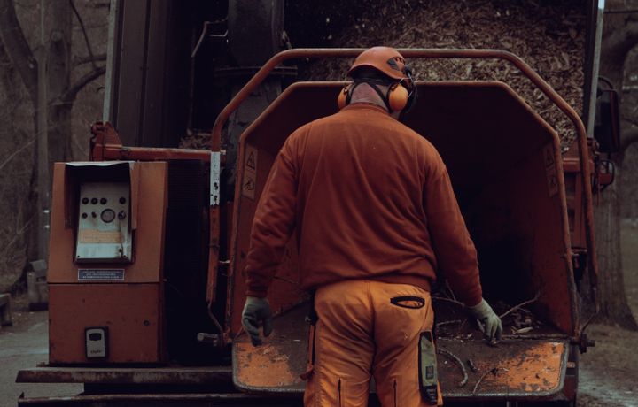 A crew member feeding branches into a wood chipper